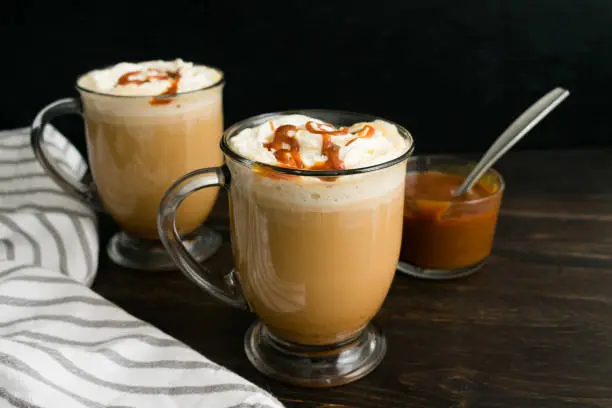Coffee with milk topped with whipped cream and caramel sauce