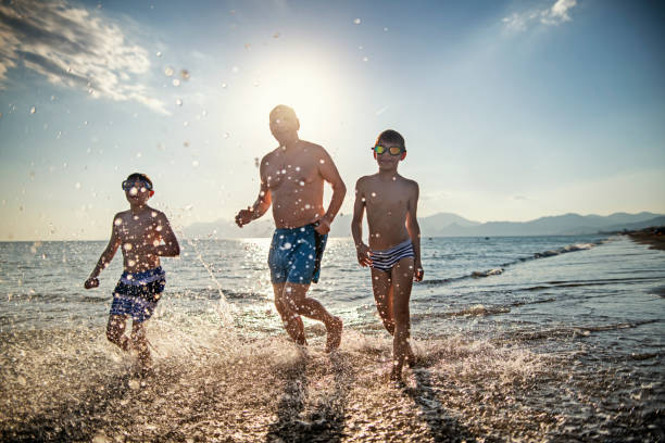 istock Senior man running with grandsons in sea 1185896650