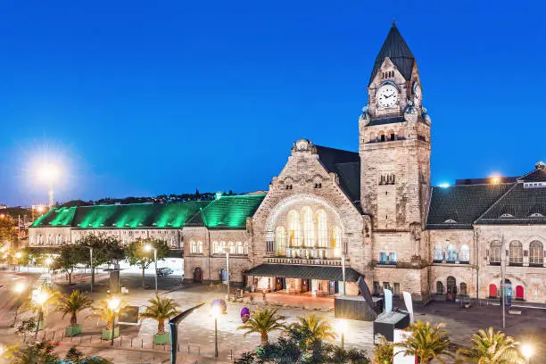 Night view of the illuminated old railway station building with clock tower in Metz city