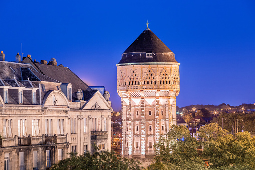 Cityscape view of illuminated Old Water tower and residential houses in Metz city at night