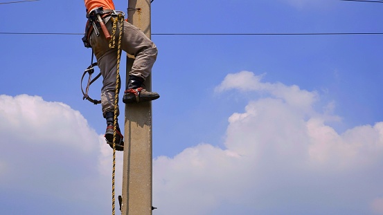 Low Section Of Electric Lineman Is Climbing On Electric Pole Stock