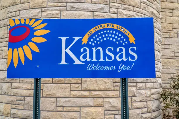 Kansas welcomes you - welcome roadside sign at freeway rest area with a popular Latin phrase ad astra per aspera (through hardships to the stars), driving and travel concept