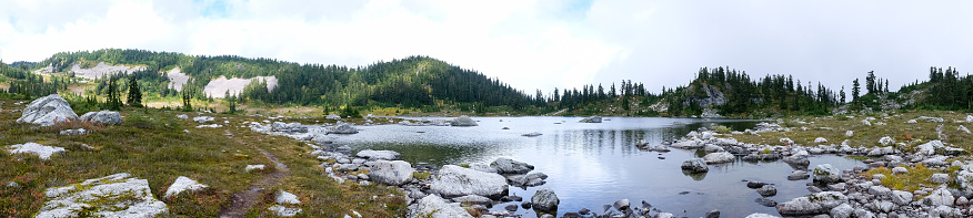 A small mountain lake lies in a valley in the British Columbia Mountains. Panoramic landscape.