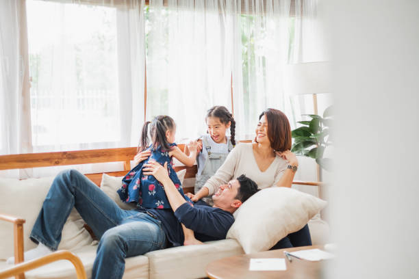 happy asian family playing together at sofa, home living room - asian ethnicity child four people couple imagens e fotografias de stock