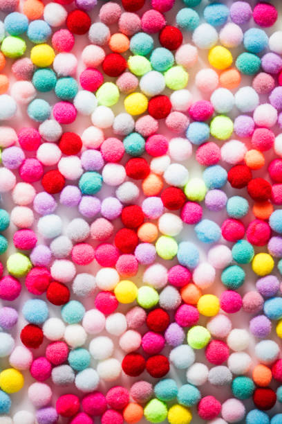 istock Texture of small colorful textile fluffy pompons on a white background. Flat lay. Creative. 1185910735