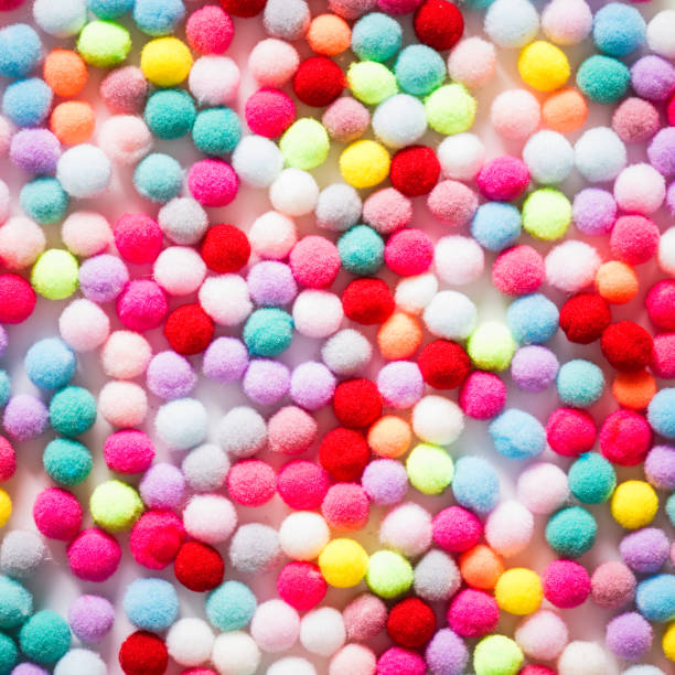 istock Texture of small colorful textile fluffy pompons on a white background. Flat lay. Creative. 1185910743