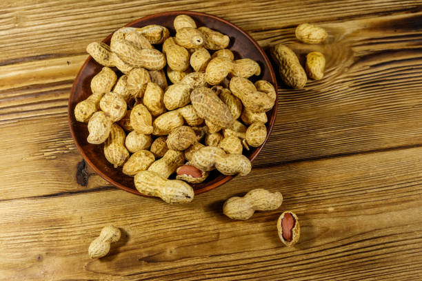 istock Peanuts in nutshell on a wooden table. Top view 1185921490