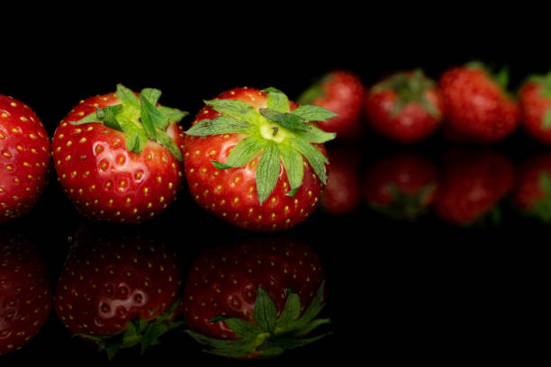 istock Fresh red strawberry isolated on black glass 1185921695