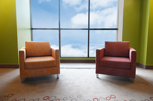 Two soft chairs in a large panoramic window. View of the sky and clouds.