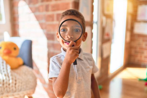 piękny afroamerykański maluch bawiący się lupą w przedszkolu - curiosity searching discovery home interior zdjęcia i obrazy z banku zdjęć