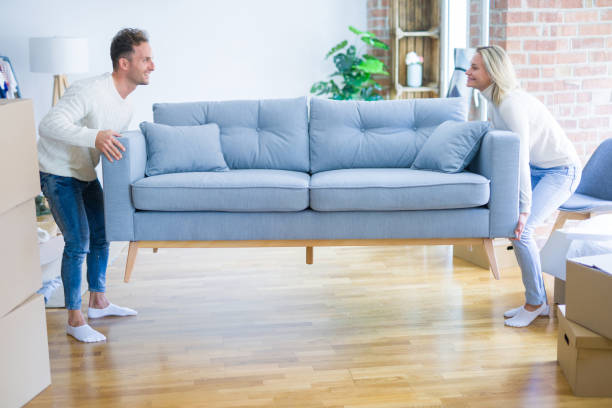 istock Young beautiful couple moving sofa at new home around cardboard boxes 1185924374