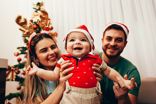 Young family celebrating Christmas at home. Happy young family enjoying their holiday time together.