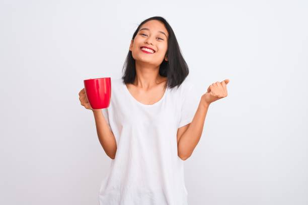 Young beautiful chinese woman drinking cup of coffee over isolated white background screaming proud and celebrating victory and success very excited, cheering emotion Young beautiful chinese woman drinking cup of coffee over isolated white background screaming proud and celebrating victory and success very excited, cheering emotion hot vietnamese women pictures stock pictures, royalty-free photos & images