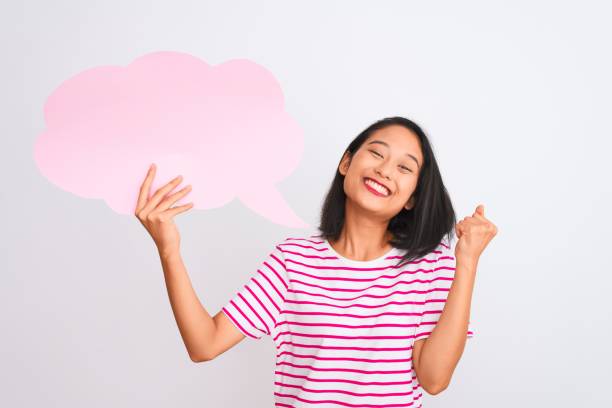 istock Young chinese woman holding cloud speech bubble standing over isolated white background screaming proud and celebrating victory and success very excited, cheering emotion 1185924708