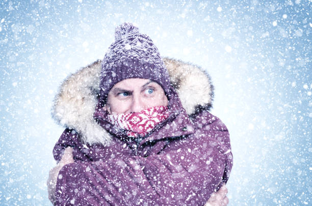 istock Frozen man in red winter clothes warms his hands, cold, snow, frost, blizzard 1185928087