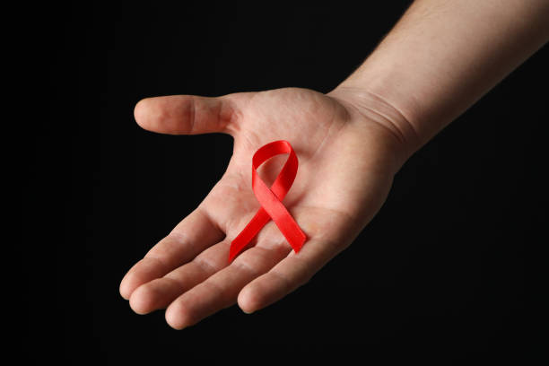 istock Hand and red awareness ribbon against black background, space for text 1185928088