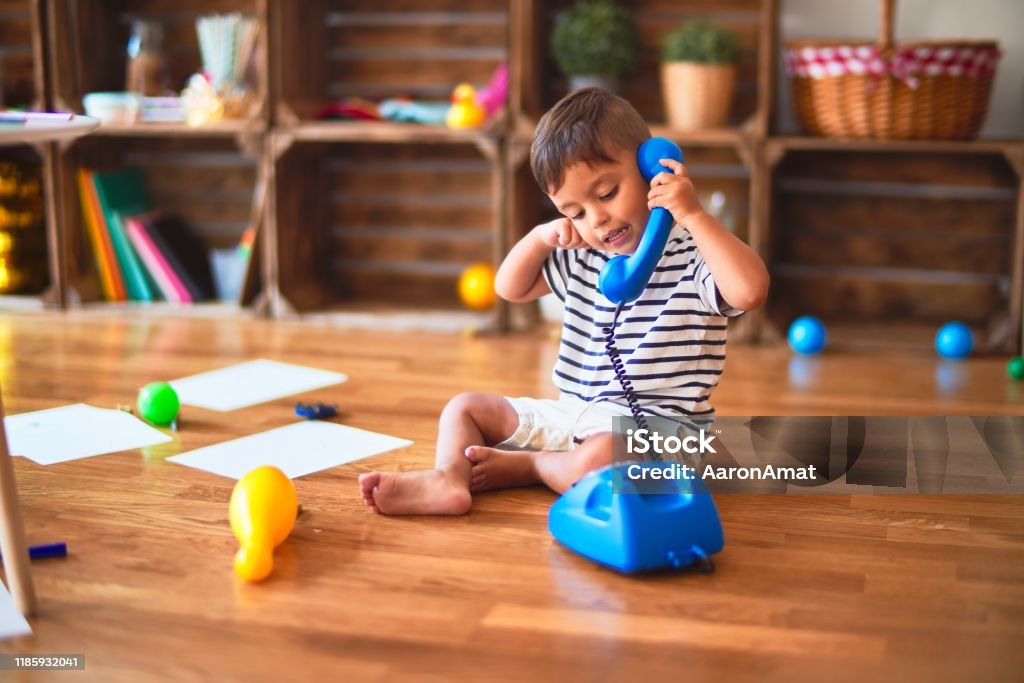 Hermoso niño niño jugando con el teléfono azul vintage en el jardín de infantes - Foto de stock de Niño libre de derechos