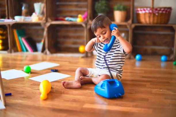 幼稚園でヴィンテージブルーの携帯電話で遊ぶ美しい幼児の少�年 - vintage telephone ストックフォトと画像