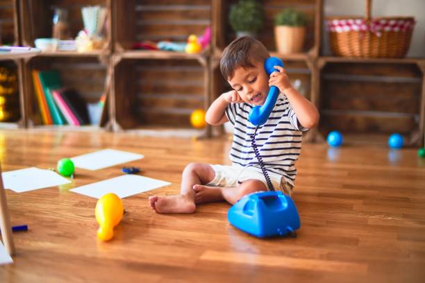 Beautiful toddler boy playing with vintage blue phone at kindergarten Beautiful toddler boy playing with vintage blue phone at kindergarten toddler stock pictures, royalty-free photos & images