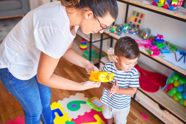 beautiful teacher and toddler using alarm clock at kindergarden - preschooler child playing latin american and hispanic ethnicity imagens e fotografias de stock