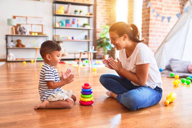 beautiful teacher and toddler boy building pyramid with hoops bolcks at kindergarten - preschooler child playing latin american and hispanic ethnicity imagens e fotografias de stock