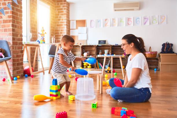 istock Beautiful teacher and toddler boy playing drum using skitlle and plastic basket at kindergarten 1185932568