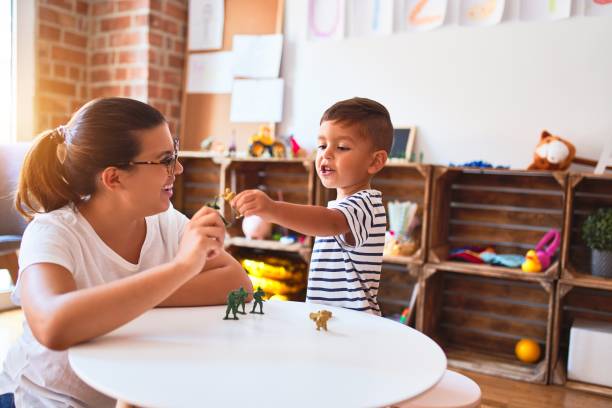 beautiful teacher and toddler boy playing with figurine army soldiers at kindergarten - preschooler child playing latin american and hispanic ethnicity imagens e fotografias de stock