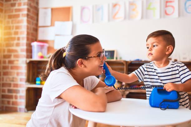beautiful teacher and toddler boy playing with vintage blue phone at kindergarten - preschooler child playing latin american and hispanic ethnicity imagens e fotografias de stock