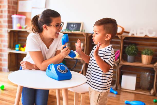 beautiful teacher and toddler boy playing with vintage blue phone at kindergarten - preschooler child playing latin american and hispanic ethnicity imagens e fotografias de stock