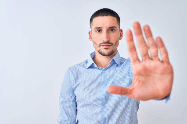 istock Young handsome business man standing over isolated background doing stop sing with palm of the hand. Warning expression with negative and serious gesture on the face. 1185933379