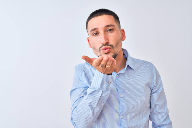 istock Young handsome business man standing over isolated background looking at the camera blowing a kiss with hand on air being lovely and sexy. Love expression. 1185933422