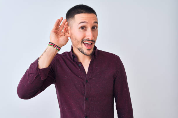 istock Young handsome business man standing over isolated background smiling with hand over ear listening an hearing to rumor or gossip. Deafness concept. 1185934068