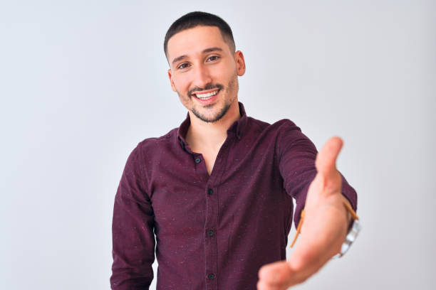 istock Young handsome business man standing over isolated background smiling friendly offering handshake as greeting and welcoming. Successful business. 1185934169