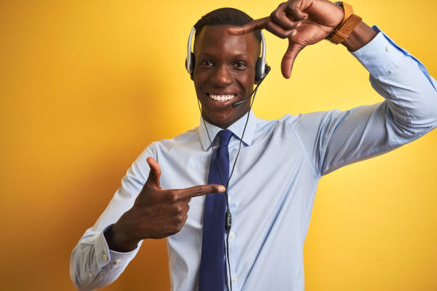 istock African american operator man working using headset over isolated yellow background smiling making frame with hands and fingers with happy face. Creativity and photography concept. 1185936705