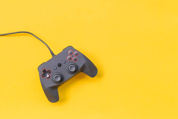 Black joysticks on yellow background. Computer game competition. Gaming concept. Place for text. Flat lay, top view, copy space.