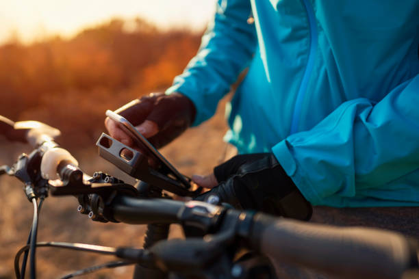 ein nicht wiederzuerkennender mountainbiker, der sein handy an einer fahrradhalterung befestigt - recreational pursuit mountain biking nature outdoors stock-fotos und bilder