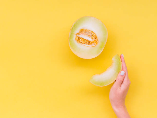 la mano della donna tiene una fetta di melone. vista dall'alto. mangiare pulito, concetto di cibo vegetariano. - mature women isolated mature adult women foto e immagini stock