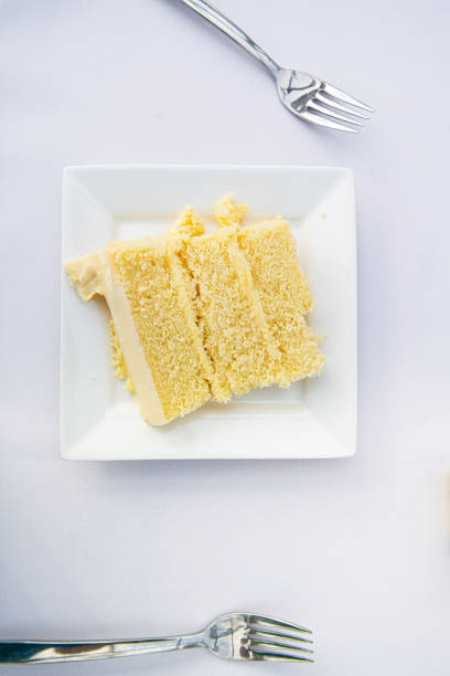 istock Flat top closeup of table setting lay view down of restaurant or wedding reception white table tablecloth one plate with vanilla cream cake slice and forks 1185937833