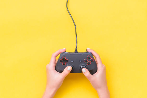istock Hands Holding Gamepad. Black joysticks on yellow background. Computer game competition. Gaming concept. Place for text. Flat lay, top view, copy space. 1185938557