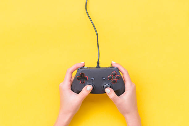 Hands Holding Gamepad. Black joysticks on yellow background. Computer game competition. Gaming concept. Place for text. Flat lay, top view, copy space. Hands Holding Gamepad. Black joysticks on yellow background. Computer game competition. Gaming concept. Place for text. Flat lay, top view gamepad photos stock pictures, royalty-free photos & images