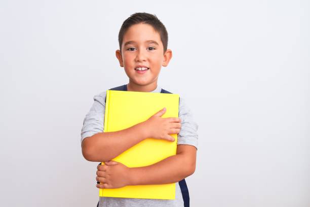 istock Beautiful student kid boy wearing backpack holding book over isolated white background with a happy face standing and smiling with a confident smile showing teeth 1185940365