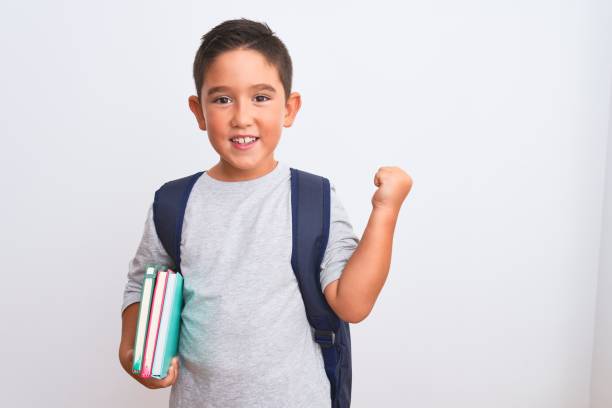 istock Beautiful student kid boy wearing backpack holding books over isolated white background screaming proud and celebrating victory and success very excited, cheering emotion 1185940383