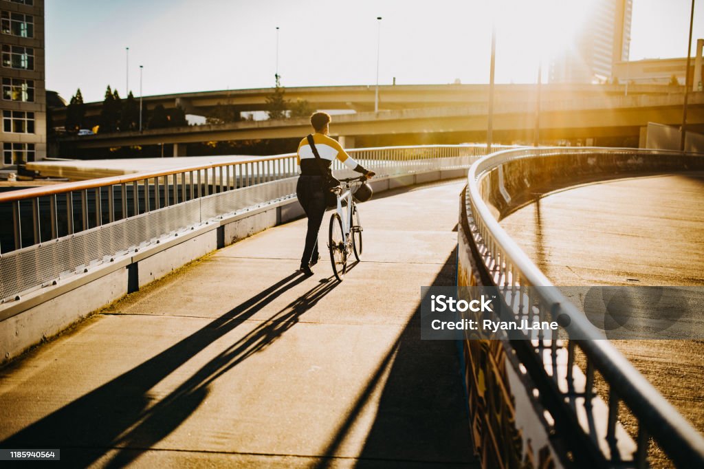 Young Woman With Bike and Messenger Bag in The City A beautiful young African American woman enjoys a sunny autumn day in downtown Tacoma, Washington, using her bike for transportation to go to class or work. Tacoma Stock Photo