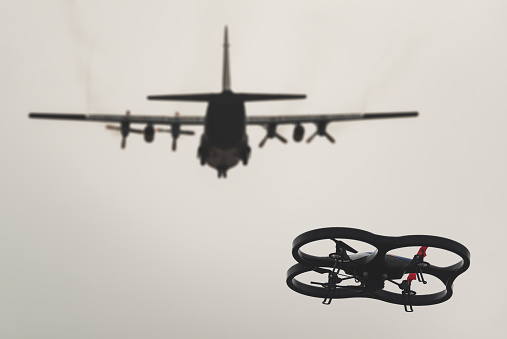 Toy drone flying beneath a plane on final approach to an airport. (Simulated composite image)