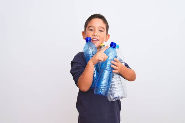 istock Beautiful kid boy recycling plastic bottles standing over isolated white background very happy pointing with hand and finger to the side 1185940953