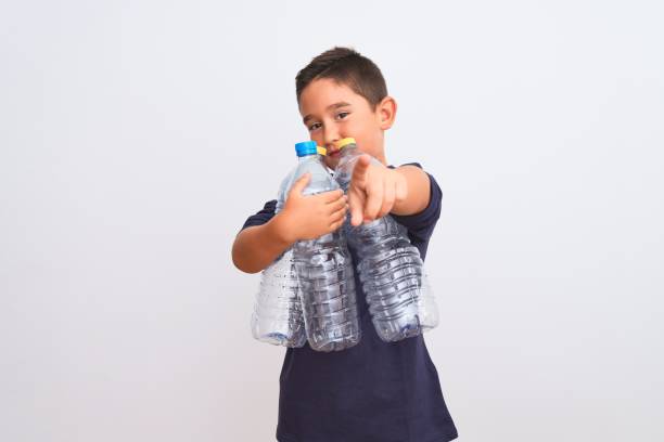 istock Beautiful kid boy recycling plastic bottles standing over isolated white background pointing with finger to the camera and to you, hand sign, positive and confident gesture from the front 1185940963