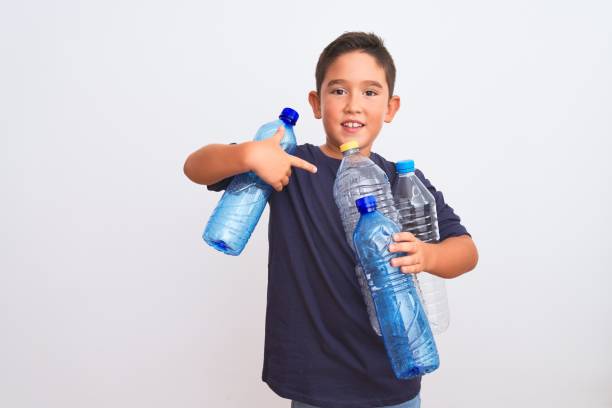 istock Beautiful kid boy recycling plastic bottles standing over isolated white background very happy pointing with hand and finger 1185940993