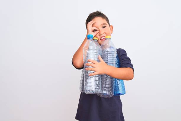 istock Beautiful kid boy recycling plastic bottles standing over isolated white background with happy face smiling doing ok sign with hand on eye looking through fingers 1185941049