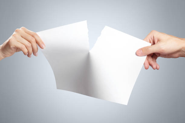 istock Hands tearing white paper on gray 1185942734