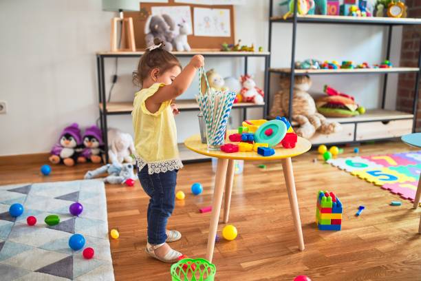 istock Beautiful toddler playing with striped straws standing at kindergarten 1185943009